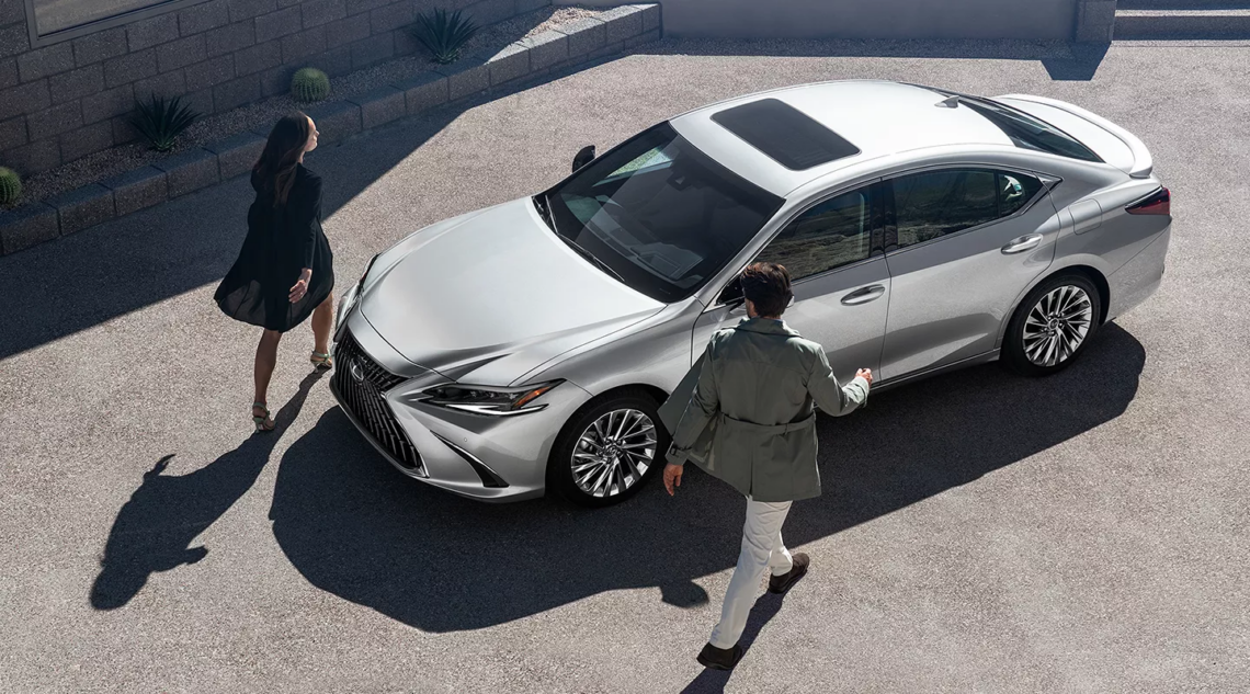 overhead image of two people approaching a silver Lexus ES
